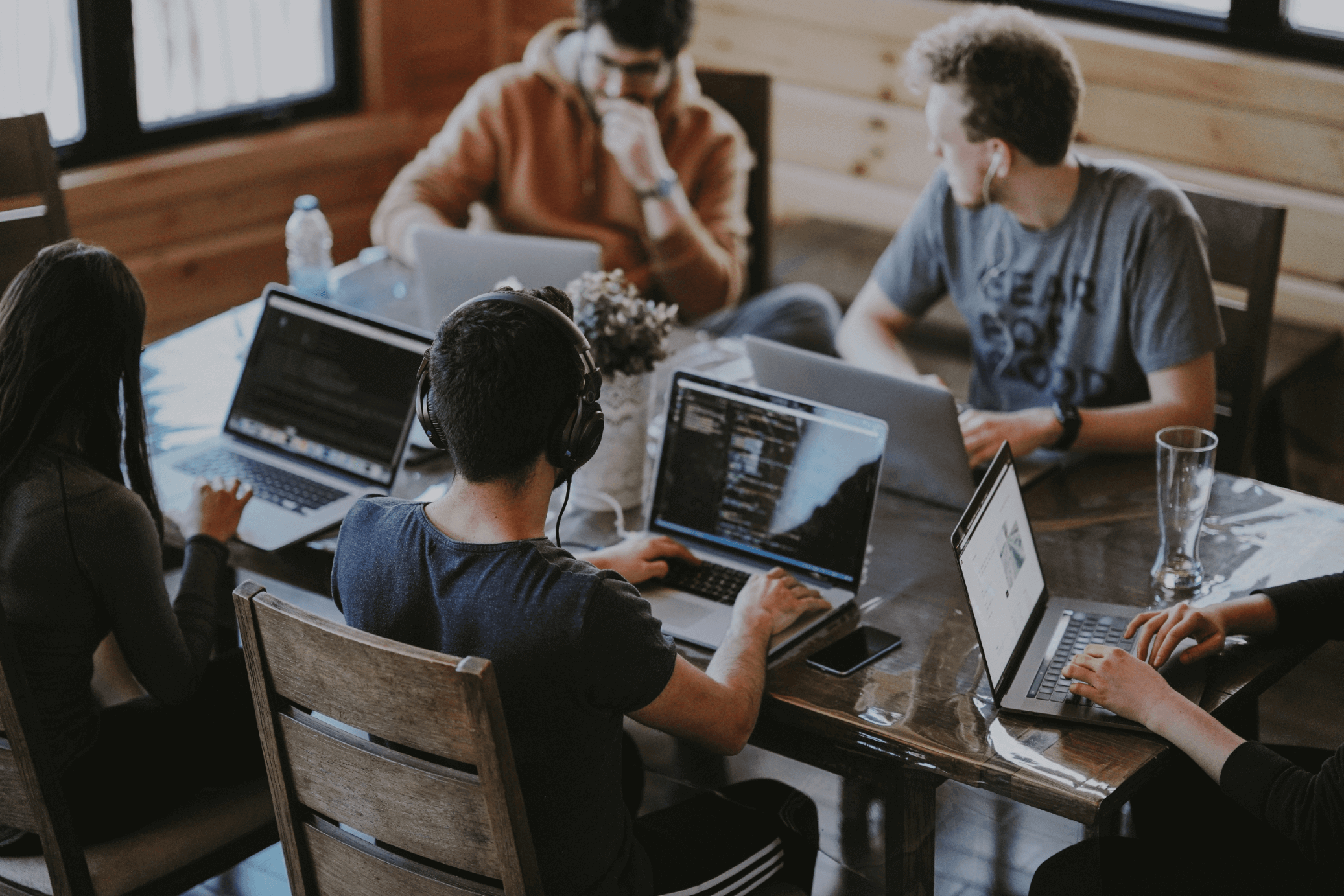 Equipe trabalhando em notebooks numa mesa compartilhada de escritório