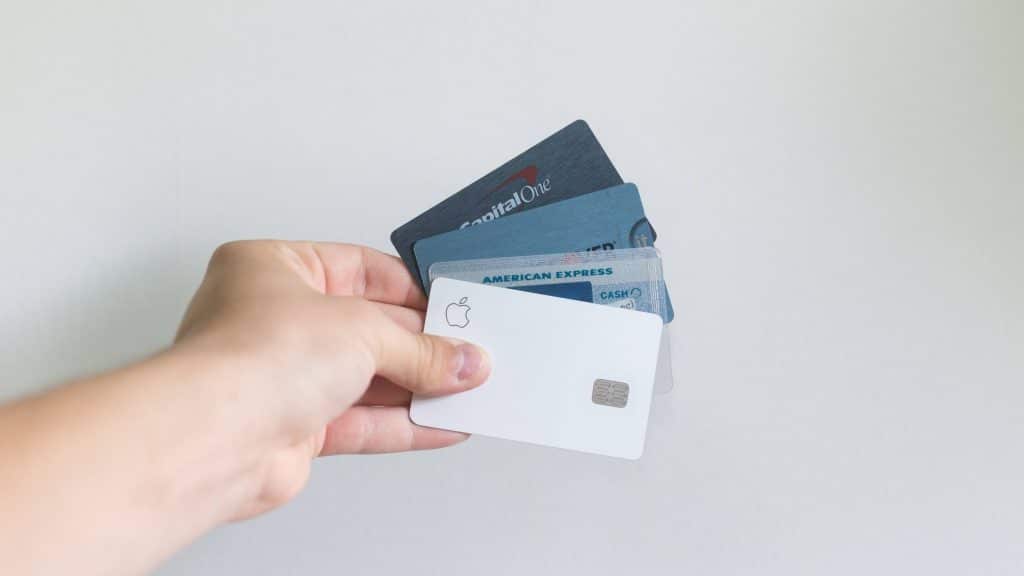 mão segurando cartões de crédito com parede branca de fundo