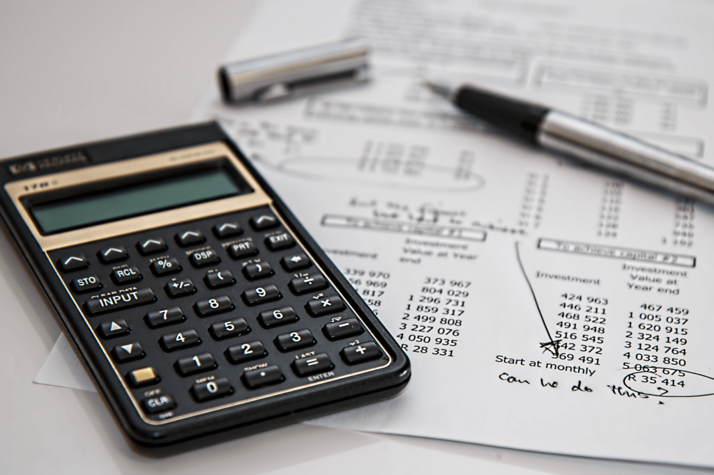 Foto de calculadora e documentos representando o controle de fluxo de caixa, gestão financeira de empresas e o planejamento financeiro empresarial das finanças corporativas
