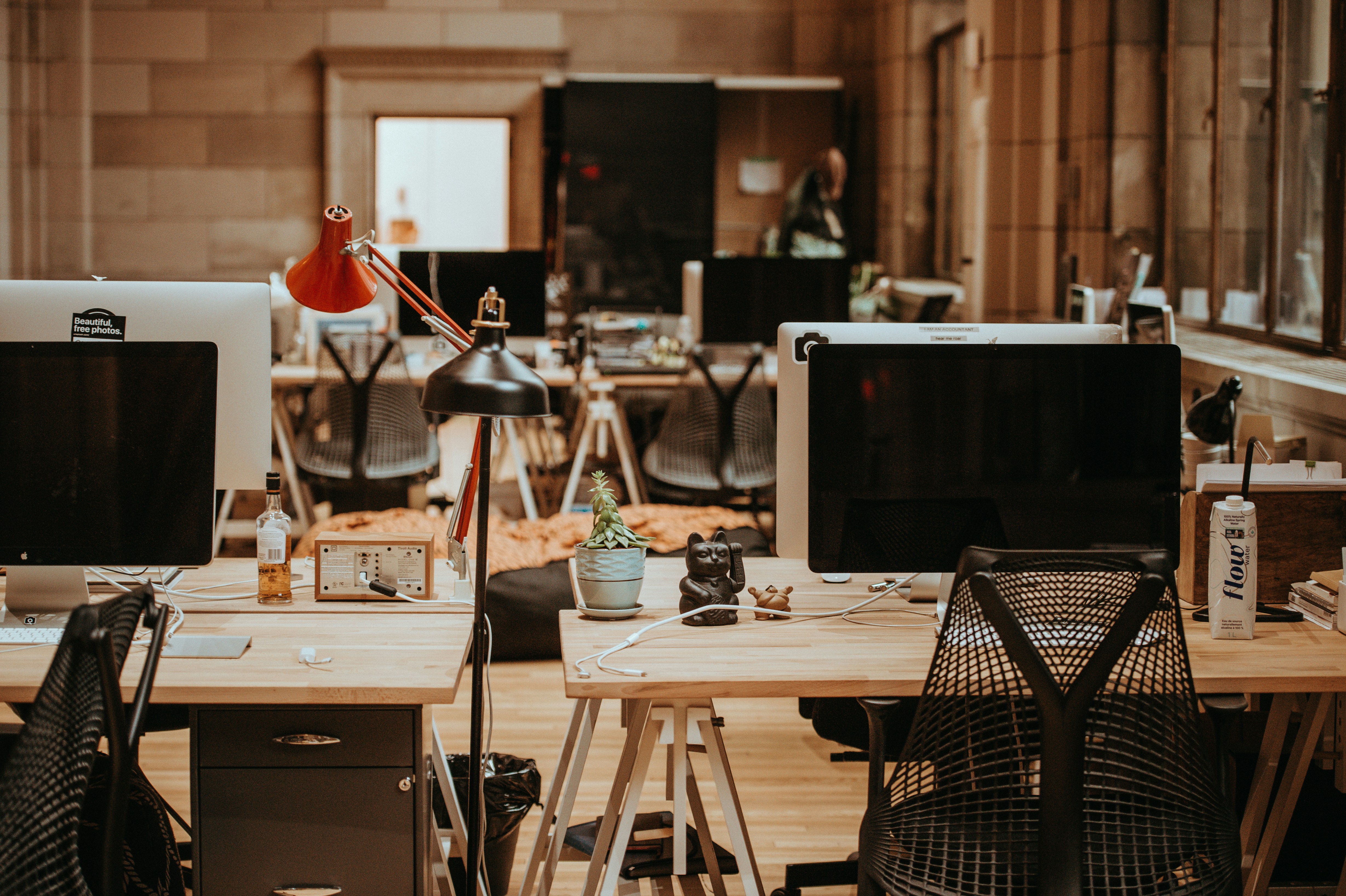 Ambiente de escritório moderno e aconchegante com várias mesas, cadeiras e computadores. A combinação de tecnologia e conforto define esse espaço de trabalho contemporâneo.