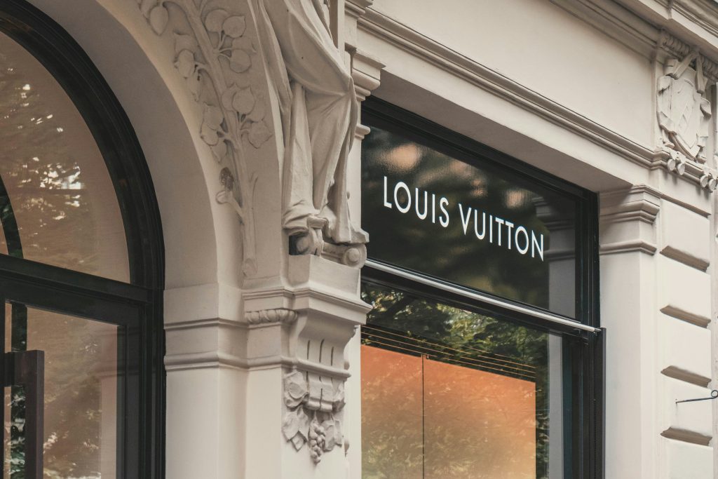 elegante fachada de uma loja Louis Vuitton, destacando o contraste entre o moderno letreiro iluminado da marca e os detalhes arquitetônicos clássicos do edifício