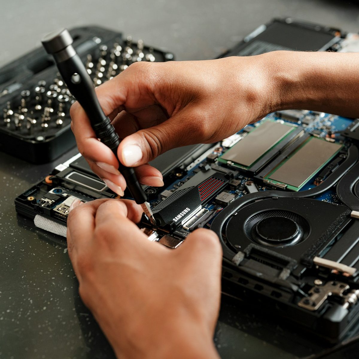 Técnico de informática trabalhando na manutenção de um notebook em bancada especializada.