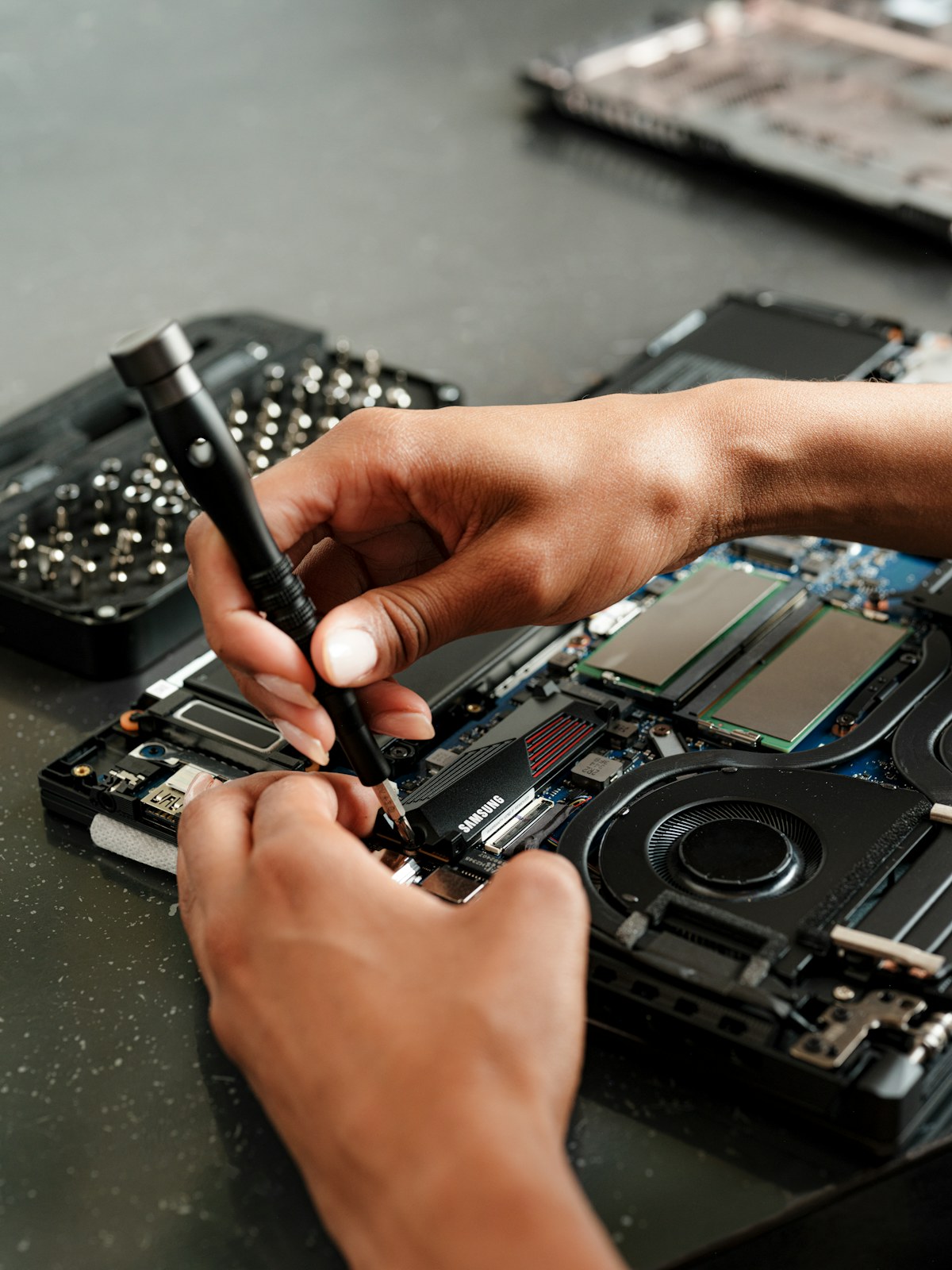 Técnico de informática trabalhando na manutenção de um notebook em bancada especializada.