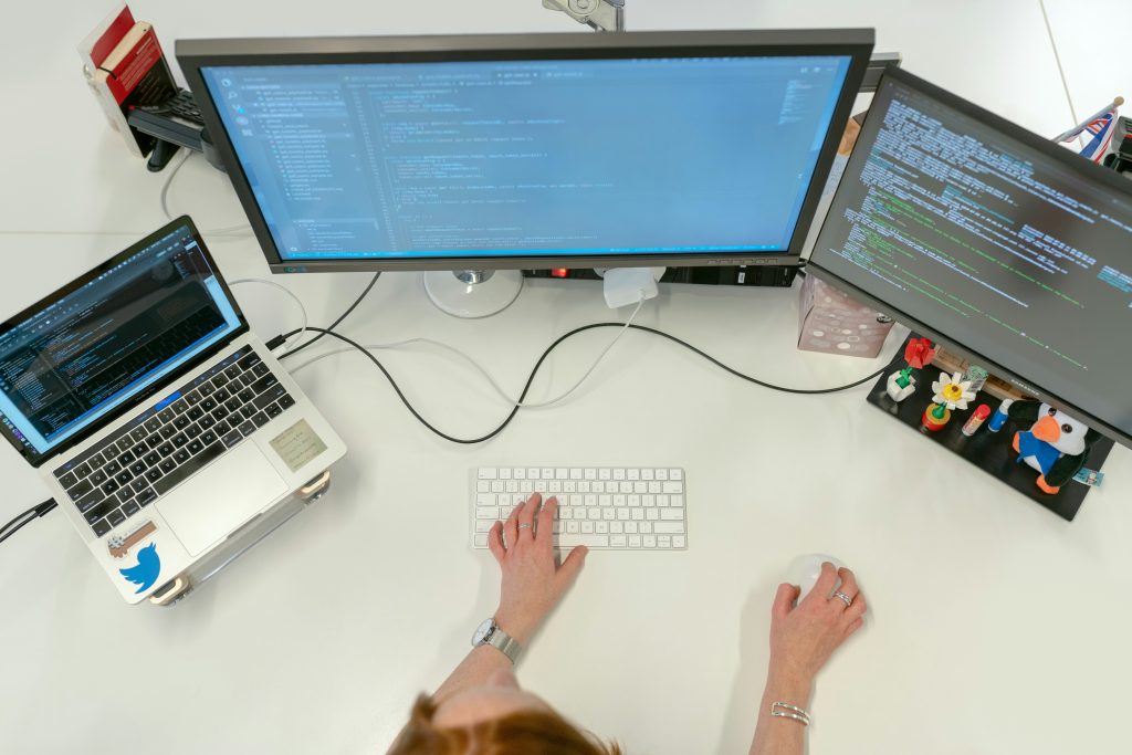 Mulher em frente ao computador com três telas indicando alguém que trabalha no suporte para auxiliar os clientes do eGestor com API